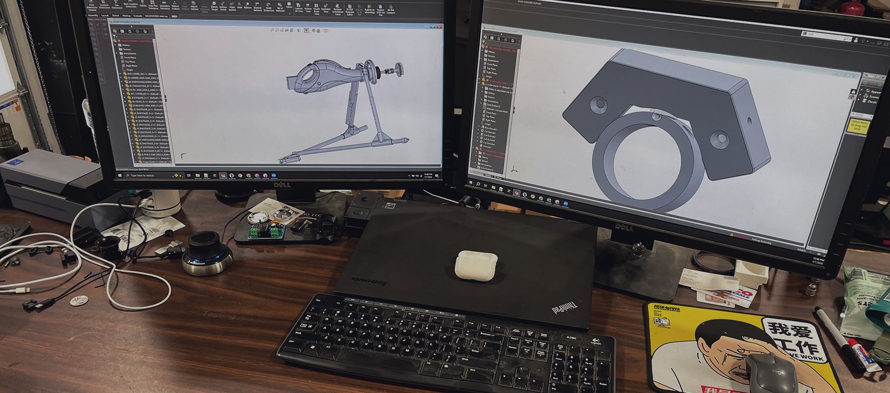 desk with two monitors displaying CAD files